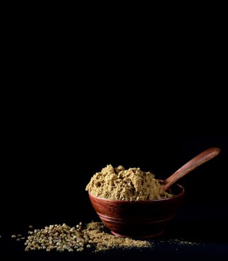 Kişniş tohumu ve kil kapta kişniş tozu veya koyu arkaplanda kase.