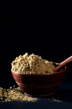 Kişniş tohumu ve kil kapta kişniş tozu veya koyu arkaplanda kase.