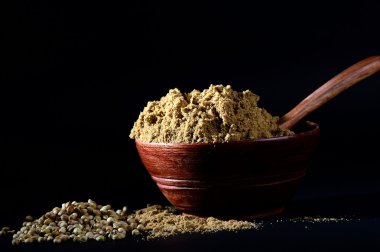 Kişniş tohumu ve kil kapta kişniş tozu veya koyu arkaplanda kase.