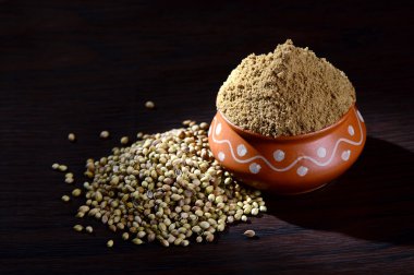 Kişniş tohumu ve kil kapta kişniş tozu veya koyu arkaplanda kase.