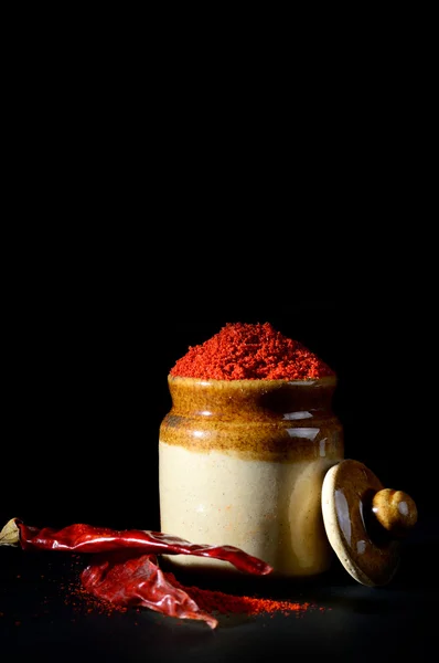 Червоний перець порошок в глиняний горщик з червоним перцем Чилі на чорному фоні — стокове фото