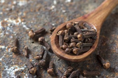 Ahşap bir kaşıkta karanfiller dokulu bir arka planda 