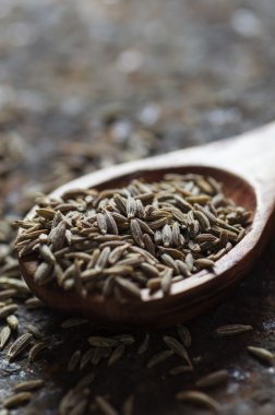 Ahşap kaşıkta kimyon tohumları dokulu bir arka planda 