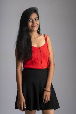 Gri arka planda poz veren kırmızı ve siyah elbiseli güzel bir kız..