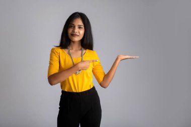 Mutlu gülümseyen bir yüzle elinde bir şey tutan ve sunan başarılı, neşeli bir genç kızın portresi.