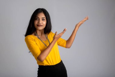 Mutlu gülümseyen bir yüzle elinde bir şey tutan ve sunan başarılı, neşeli bir genç kızın portresi.