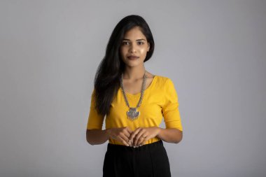 Gri arka planda poz veren genç bir kızın portresi