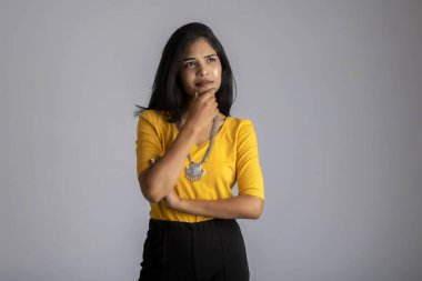 Gri arka planda düşünen genç bir kızın portresi.