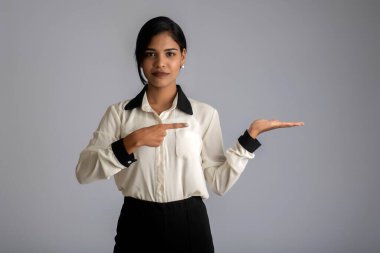 Güzel kız elinde mutlu bir gülümsemeyle bir şey tutuyor ve sunuyor..