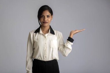 Güzel kız elinde mutlu bir gülümsemeyle bir şey tutuyor ve sunuyor..