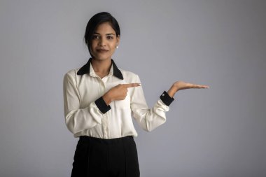 Güzel kız elinde mutlu bir gülümsemeyle bir şey tutuyor ve sunuyor..