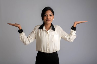 Güzel kız elinde mutlu bir gülümsemeyle bir şey tutuyor ve sunuyor..