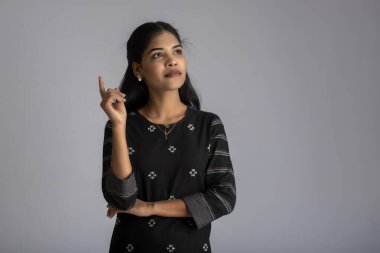 Gri arka planda poz veren genç bir kızın portresi