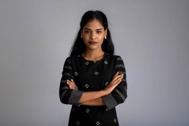 Gri arkaplanda kameraya bakıp gülümseyen güzel, neşeli bir kızın portresi.