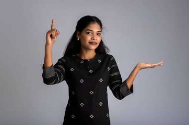 Güzel kız elinde mutlu bir gülümsemeyle bir şey tutuyor ve sunuyor..