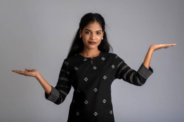 Güzel kız elinde mutlu bir gülümsemeyle bir şey tutuyor ve sunuyor..