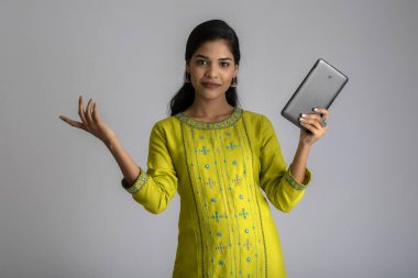 Gri arka planda cep telefonu ya da akıllı telefon kullanan genç kız