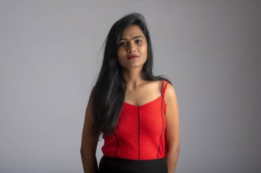 Gri arka planda poz veren kırmızı ve siyah elbiseli güzel bir kız..