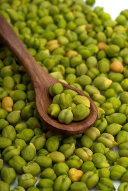 Taze yeşil nohut (Cicer arietinum) beyaz arka planda dağınık nohut ile ahşap kaşık içinde. Desi çeşidi.