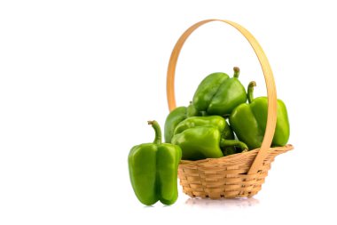 Taze yeşil dolma biber ya da beyaz arka planda bambu sepetinde kapsicum.
