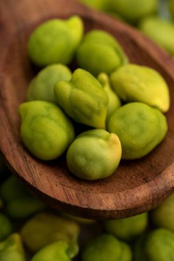 Taze yeşil nohut (Cicer arietinum) beyaz arka planda dağınık nohut ile ahşap kaşık içinde. Desi çeşidi.