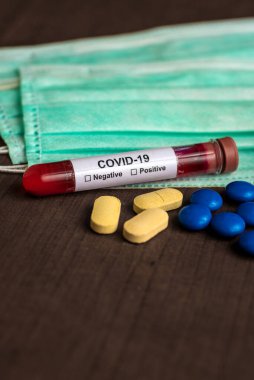 Coronavirus / COVID-19 ile Maske ve ilaç tabletini test etmek için bir kan örneği içeren tüp.