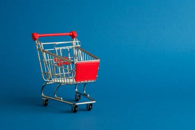Mavi arka plandaki alışveriş için boş el arabası veya alışveriş arabası.