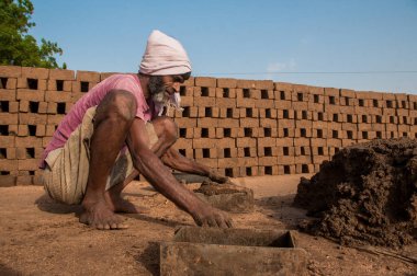 AMRAVATI, MAHARASHTRA - 24 Mayıs 2018: Kil veya çamur üzerinde işlem yapan ve tuğla fırını, fabrikası veya tarlasında geleneksel tuğlaları elle yapan tanımlanamayan Hintli işçiler.