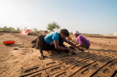 AMRAVATI, MAHARASHTRA - 24 Mayıs 2018: Fabrikada veya tarlada elle kil tuğla yapan tanımlanamayan Hintli işçiler.