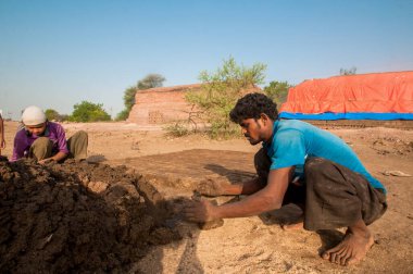 AMRAVATI, MAHARASHTRA - 24 Mayıs 2018: Fabrikada veya tarlada elle kil tuğla yapan tanımlanamayan Hintli işçiler.