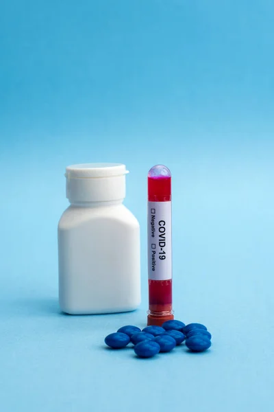A test tube filled with a blood sample for testing and bottle of pills with tablets. Coronavirus pandemic epidemic concept.
