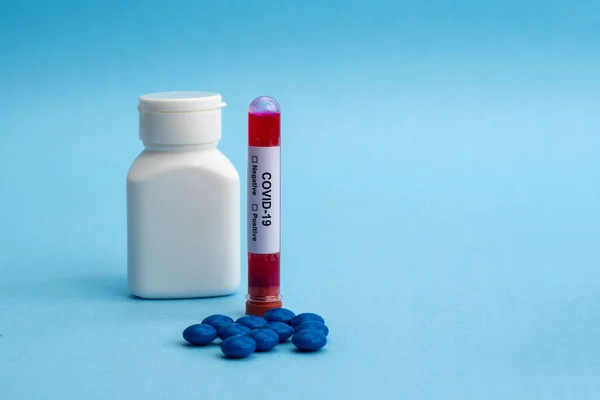 A test tube filled with a blood sample for testing and bottle of pills with tablets. Coronavirus pandemic epidemic concept.