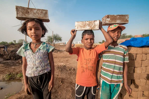 AMRAVATI, MAHARASHTRA - 24 Mayıs 2018: Kimliği belirsiz Hintli işçi çocukları tuğla ocağında veya fabrikada geleneksel tuğla yapımına yardım ediyorlar.