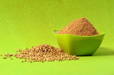 Kişniş ve yeşil zemin üzerine yeşil kap içinde Toz kişniş