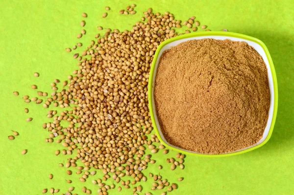 Coriander seeds and Powdered coriander in green container on green background — Stock Photo, Image