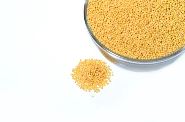 Yellow mustard seeds in glass bowl with heap — Stock Photo, Image
