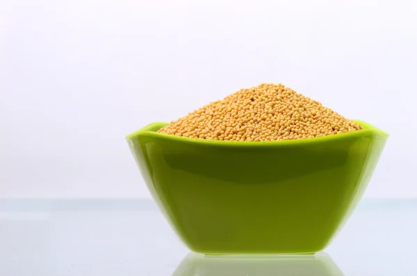 Yellow mustard seeds in green bowl — Stock Photo, Image