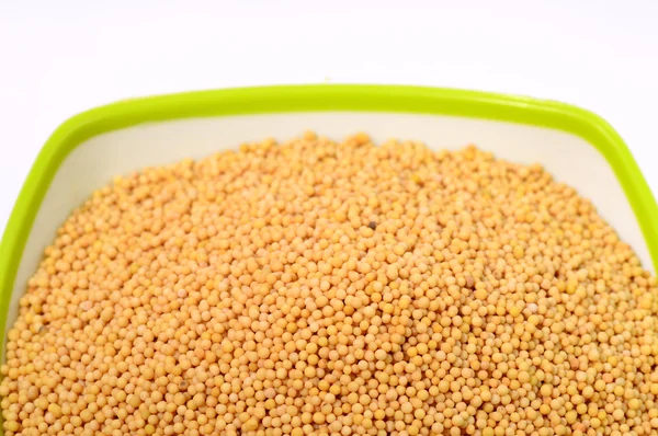 Yellow mustard seeds in green bowl — Stock Photo, Image