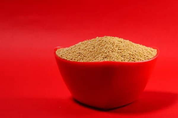 Yellow mustard seeds in red bowl