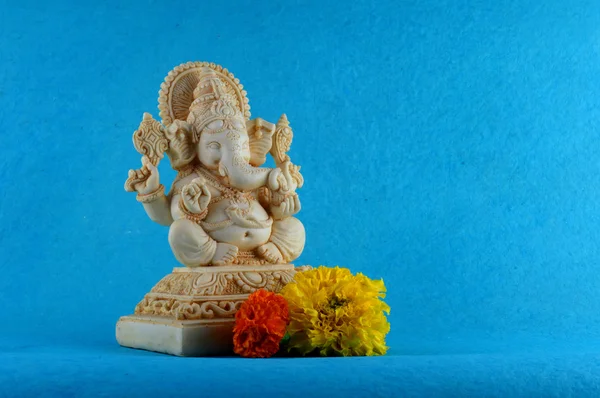 Deus Hindu Ganesha. Ganesha Idol em fundo azul com flores . — Fotografia de Stock