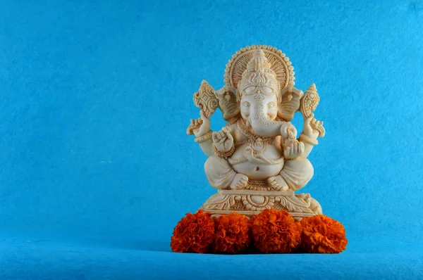 Deus Hindu Ganesha. Ganesha Idol em fundo azul com flores . — Fotografia de Stock