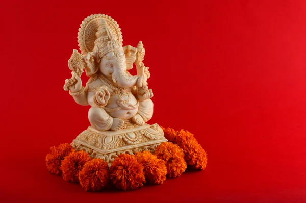 Hindoe-God Ganesha. Ganesha idool op rode achtergrond met bloemen. — Stockfoto