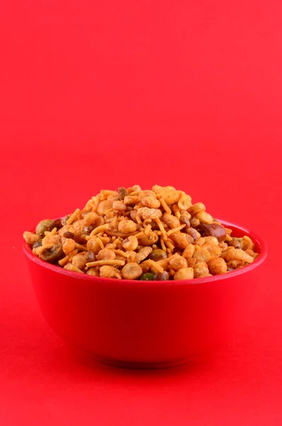 Snack indiani: Miscela (noci arrosto con sale pepe masala, legumi, channa masala dal, piselli verdi) in ciotola rossa su fondo rosso — Foto Stock