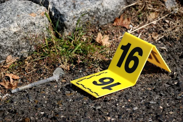 Marqueur de preuves sur les lieux du crime à côté de la seringue — Photo