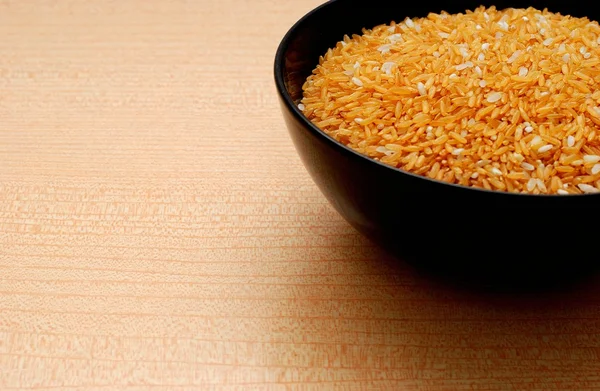 Svart skål med gult ris, Orange bakgrund — Stockfoto
