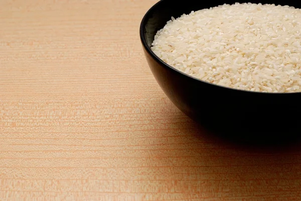Tigela preta com arroz branco, fundo laranja — Fotografia de Stock
