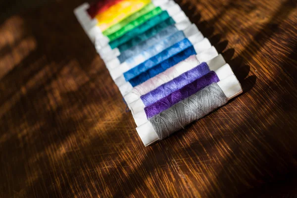 Carretel de fio de várias cores na mesa de madeira — Fotografia de Stock