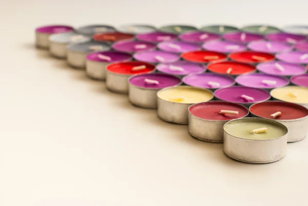 Colored Tea Candles Arranged to Triangle Shape on White Desk — Stock Photo, Image