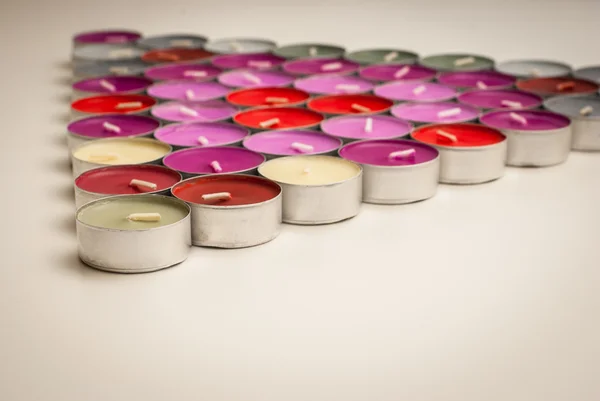 Colored Tea Candles Arranged to Triangle Shape on White Desk — Stock Photo, Image