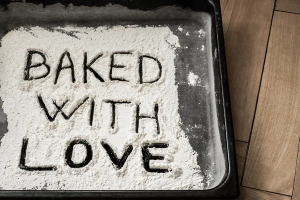 Bakat med kärlek ord skrivet på plåt täckt med vitt mjöl — Stockfoto